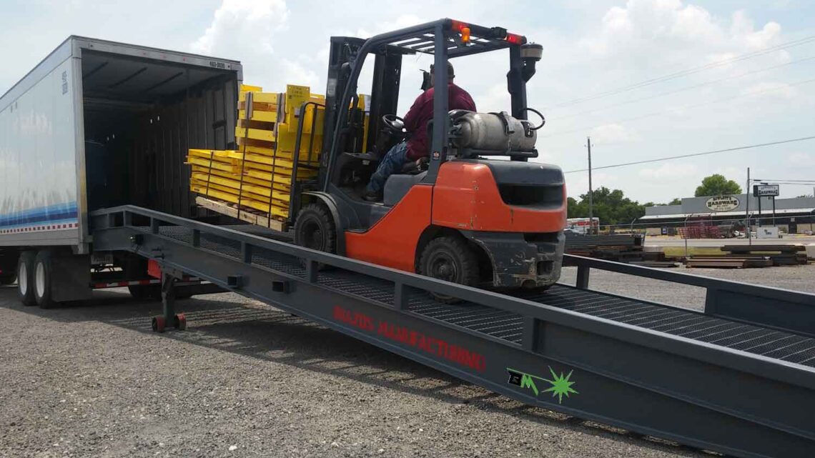 Ground to truck yard ramp with forklift truck loading truck using portable loading ramp.