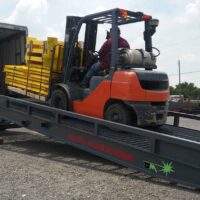 Ground to truck yard ramp with forklift truck loading truck using portable loading ramp.